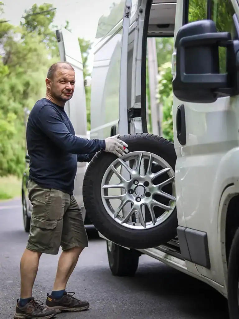 Krisztián, a Mobilgumisom alapítója kereket emel be a felszerelt mobil gumiszerviz autóba a helyszíni gumicsere során.